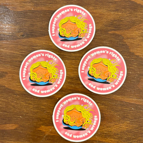 Four stickers with a graphic of a woman's face and text on a wooden surface