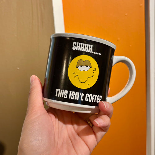 Mug with humorous design held by a hand against a neutral background