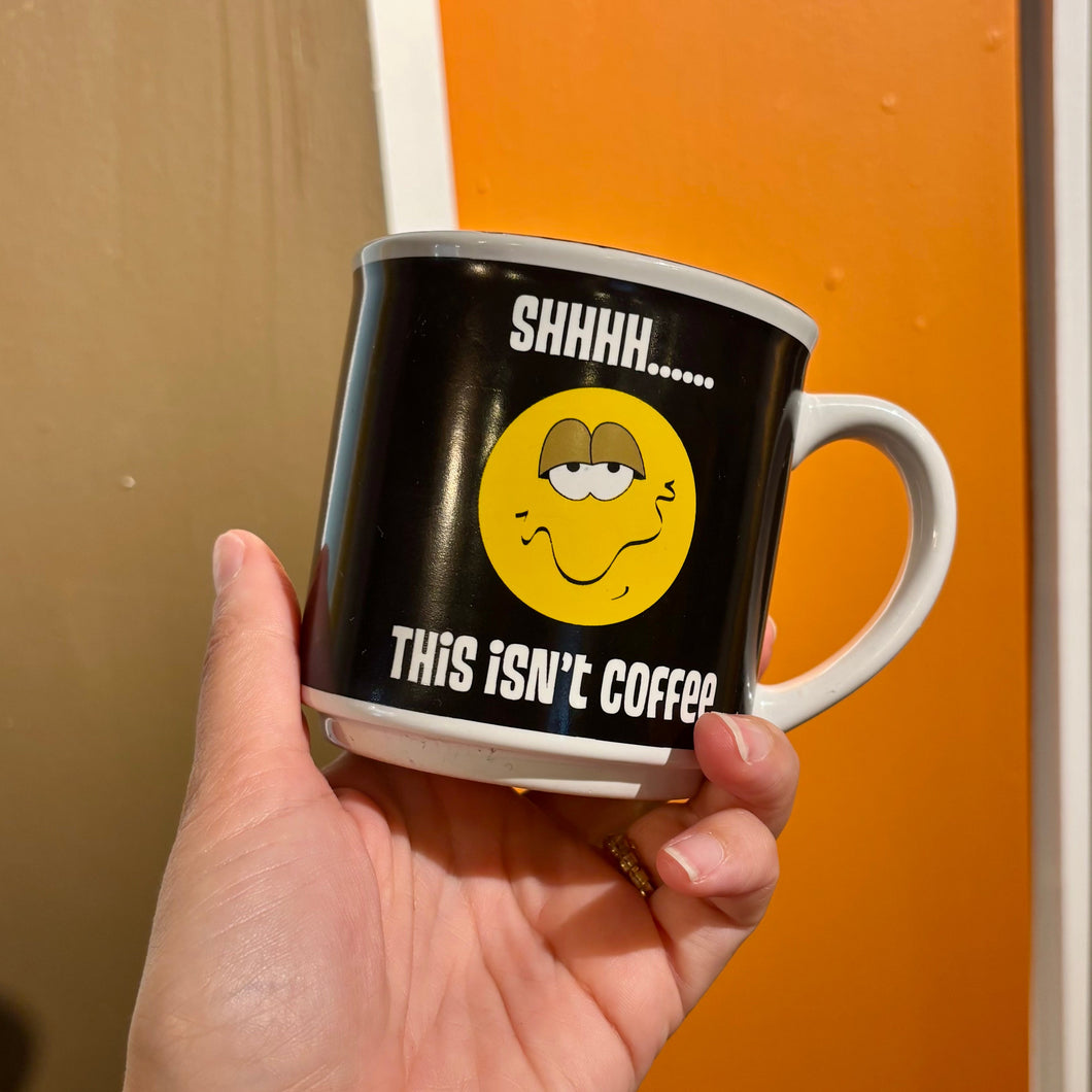 Mug with humorous design held by a hand against a neutral background