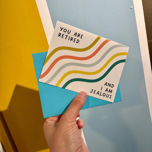 Hand holding a card with colorful wavy design and text on a blue surface.