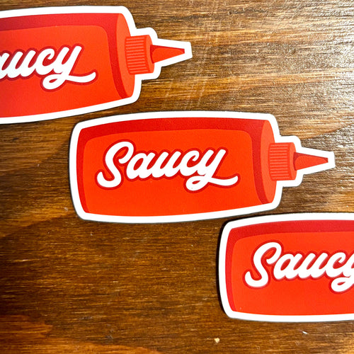 Three 'Saucy' bottle-shaped magnet on a wooden surface