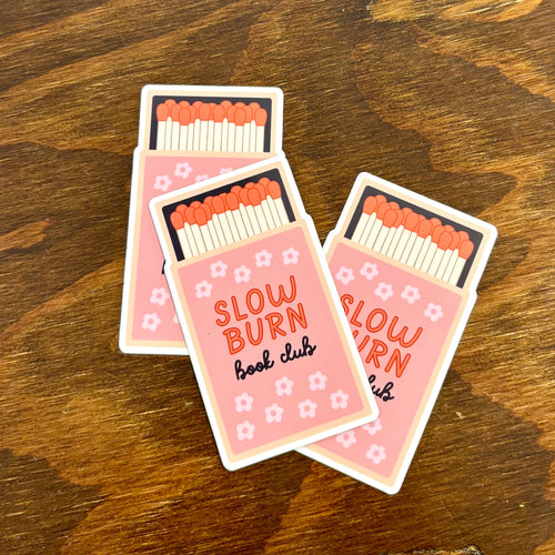 Pink matchbox-shaped magnets with 'Slow Burn Book Club' text on a wooden surface