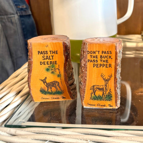 Two salt and pepper shakers with humorous labels on a table.