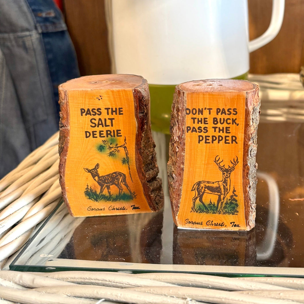 Two salt and pepper shakers with humorous labels on a table.