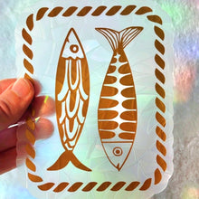 Load image into Gallery viewer, Holographic sticker with fish design held by a hand against a colorful background
