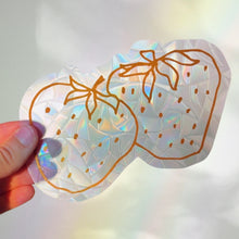 Load image into Gallery viewer, Holographic strawberry-shaped sticker held by a hand with a blurred background
